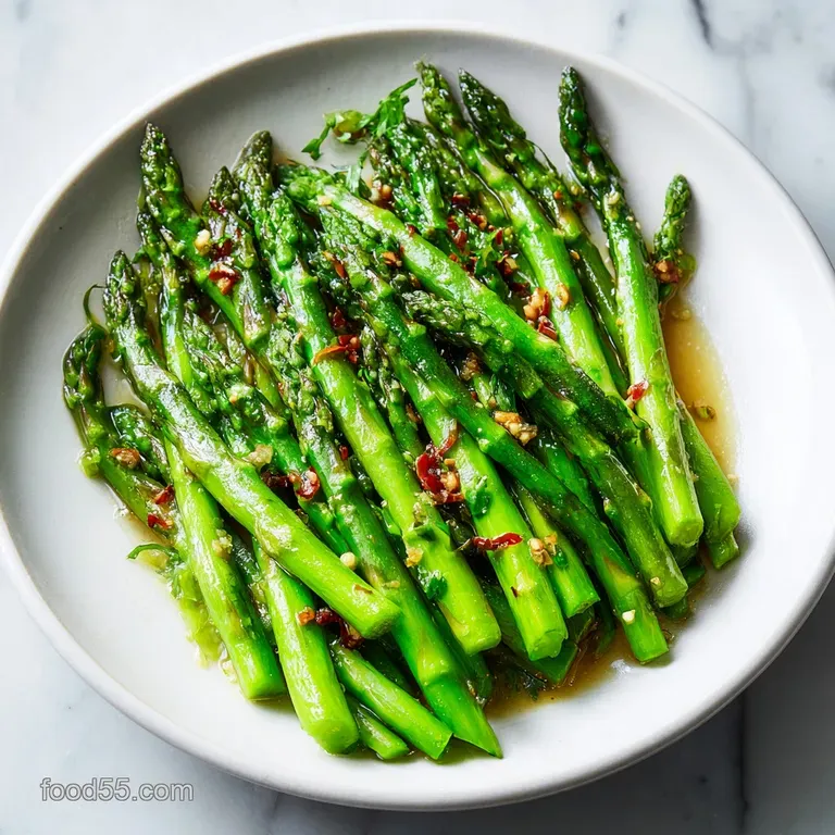A pile of bright green asparagus with golden breadcrumbs and glistening butter. Lemon wedges provide a bright contrast.