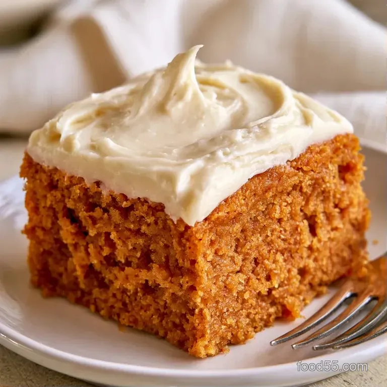 Neatly sliced orange cake squares stacked on a ceramic platter with swirls of thick, velvety white frosting.