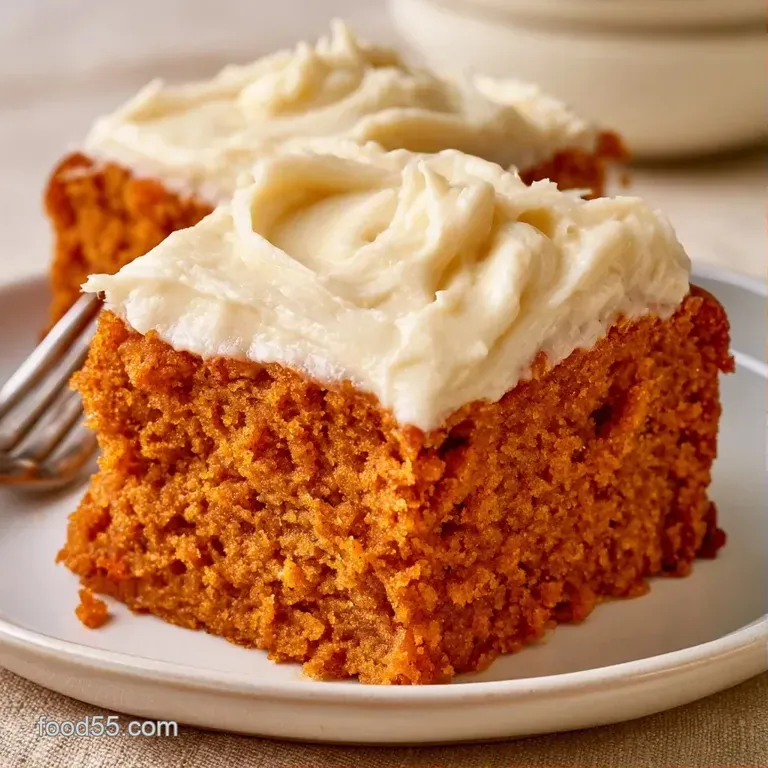 A square of spiced orange cake with swirls of white icing on a ceramic plate, garnished with a cinnamon stick.