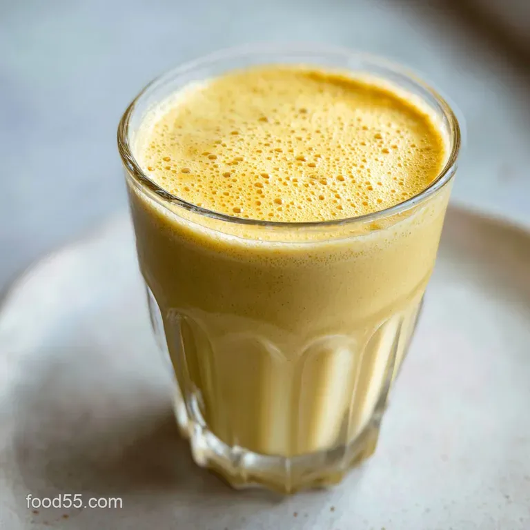 Smooth peanut butter banana drink, served in a sleek glass, with a drizzle of honey and artful banana slice garnish. Visua...