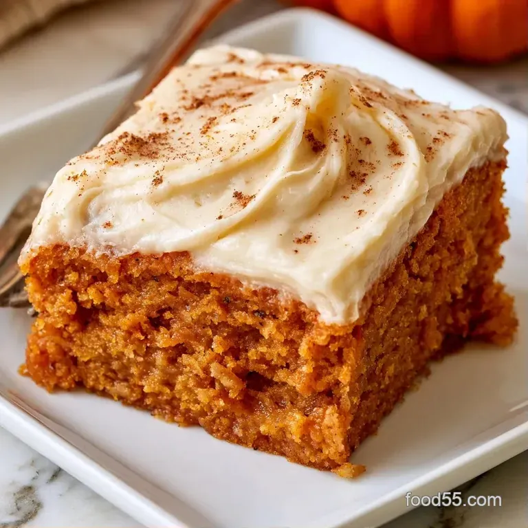A neat square of orange and white layered dessert on a slate board, accented by a dusting of warm cinnamon.