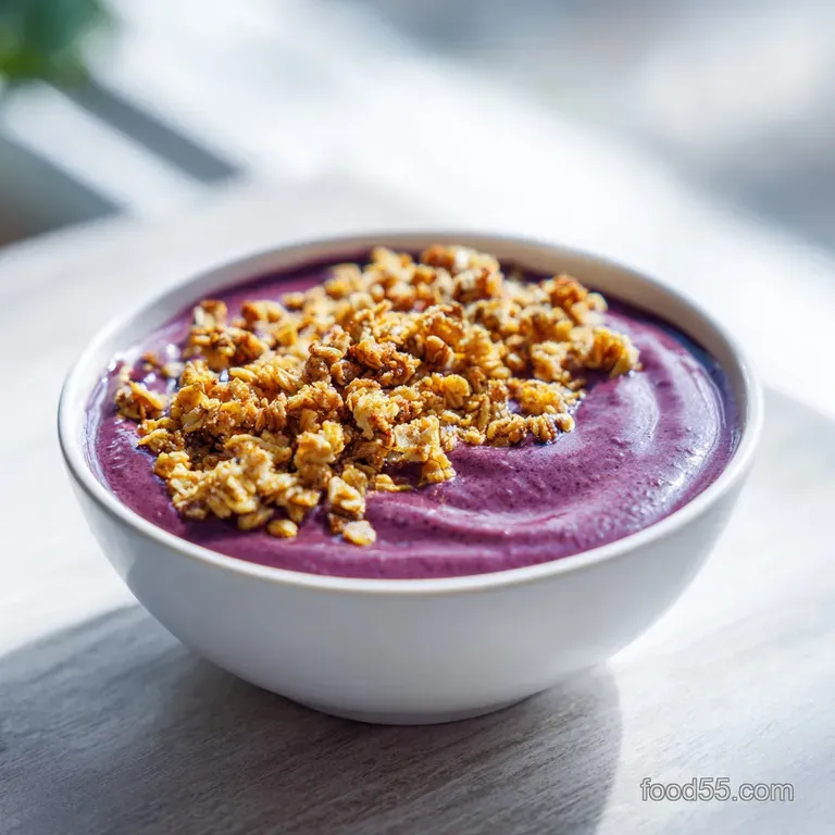Creamy pink smoothie blend in a white ceramic bowl, garnished with a swirl of almond butter and fresh kiwi slices.