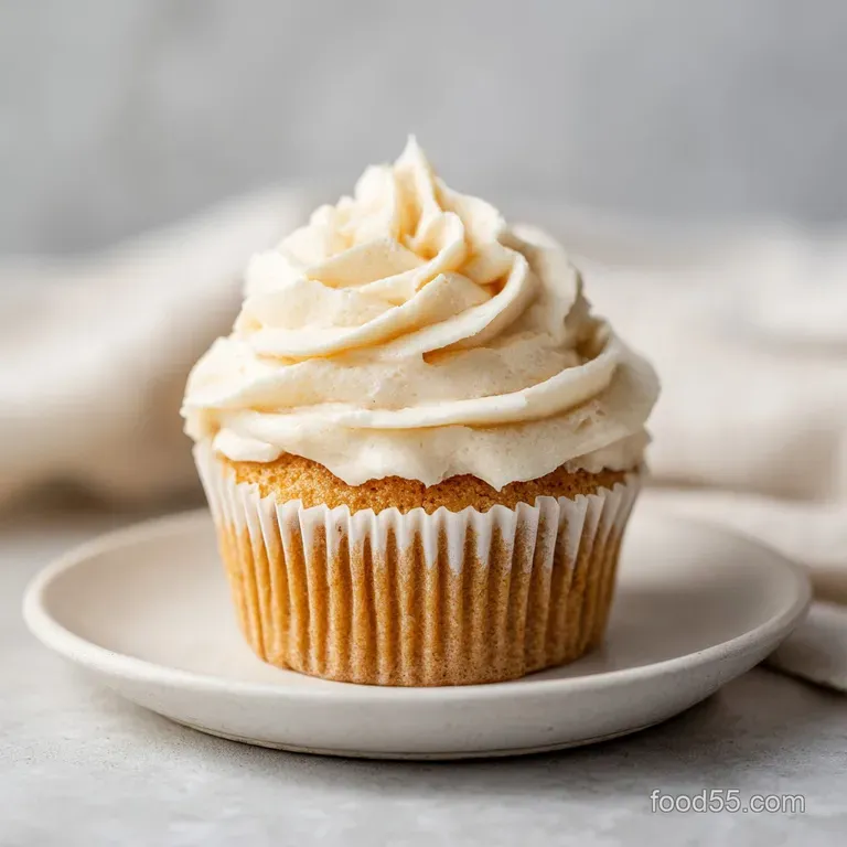Delicate piped frosting peaks crown moist cupcakes, artfully arranged on a rustic wooden board.
